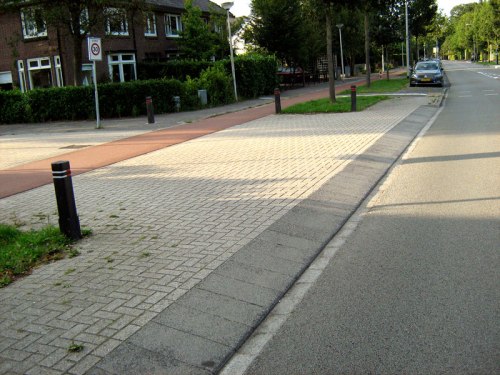 A view of a continuous-path junction from the main road. It's clear that drivers entering the minor road do not have priority over people on the footpath or bike path.